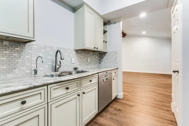 a kitchen with stainless steel appliances granite countertop a sink and white cabinets with wooden floor