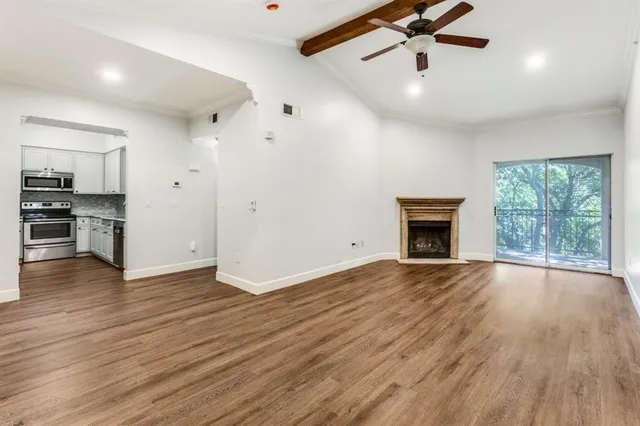 an empty room with wooden floor fireplace and windows