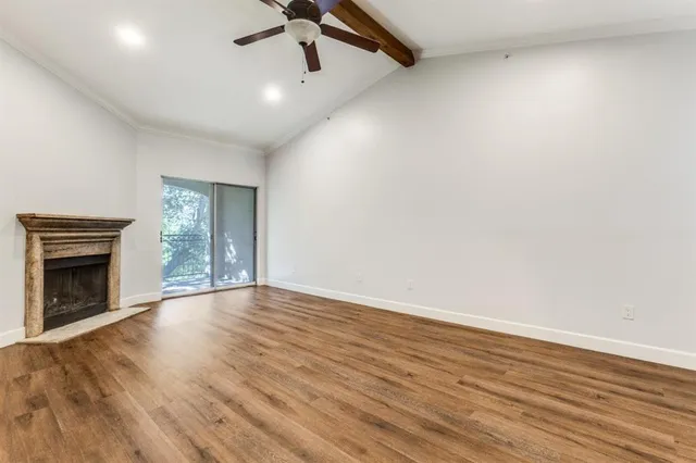 an empty room with wooden floor fireplace and windows