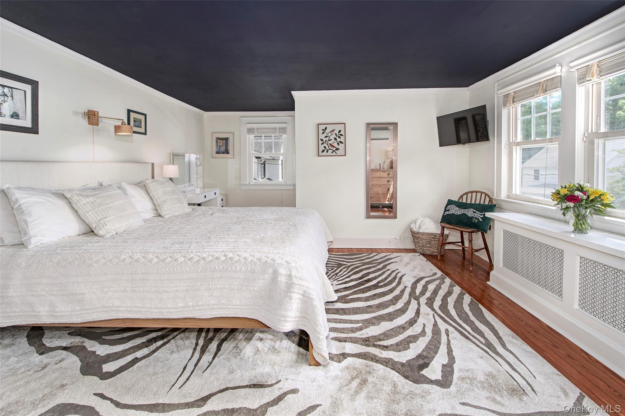 9 Fenton Street Rye, NY 10580 - Photo 16 of 22 Bright and inviting primary bedroom featuring a king-size bed, multiple windows providing abundant natural light, generous closet space, and thoughtfully selected furnishings. Designed as a comfortable retreat, the space offers a peaceful setting for rest and relaxation while maintaining the warmth and character found throughout the home.