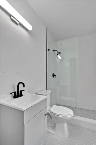 a bathroom with a toilet sink vanity and shower