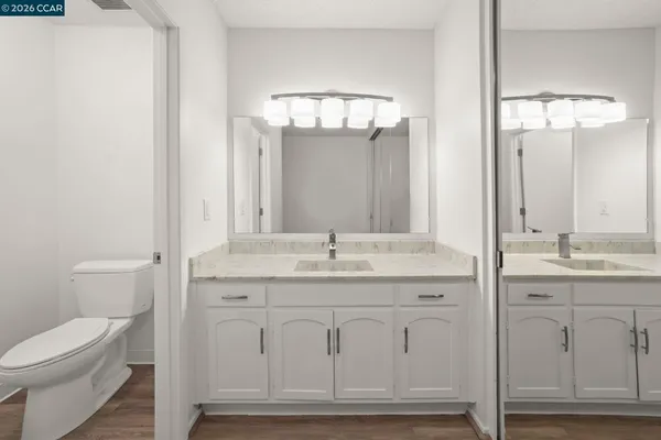 a bathroom with a granite countertop toilet a sink and a mirror