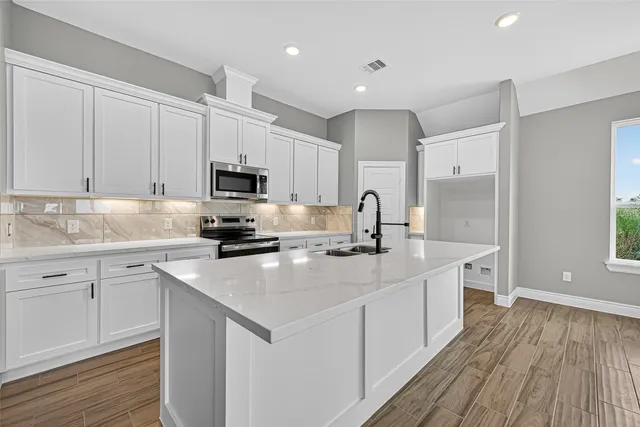 a kitchen with sink a microwave and cabinets