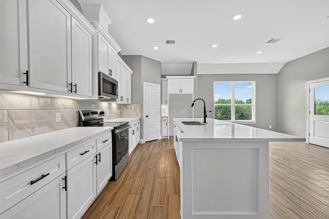 a large kitchen with kitchen island a large counter space a sink a window and stainless steel appliances