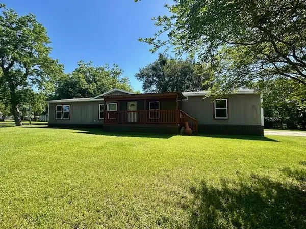 a front view of house with yard and trees in the background