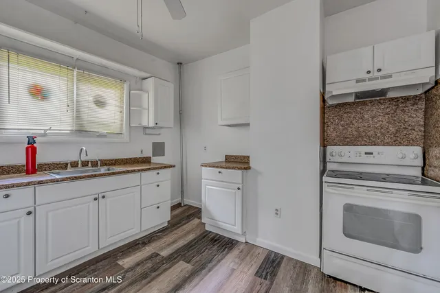 a kitchen with granite countertop white cabinets and white appliances