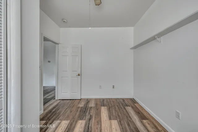 a view of an empty room with wooden floor and closet