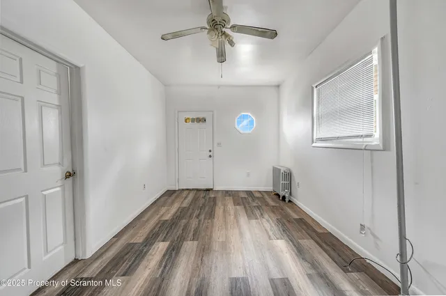 a view of a room with wooden floor ceiling fan and windows