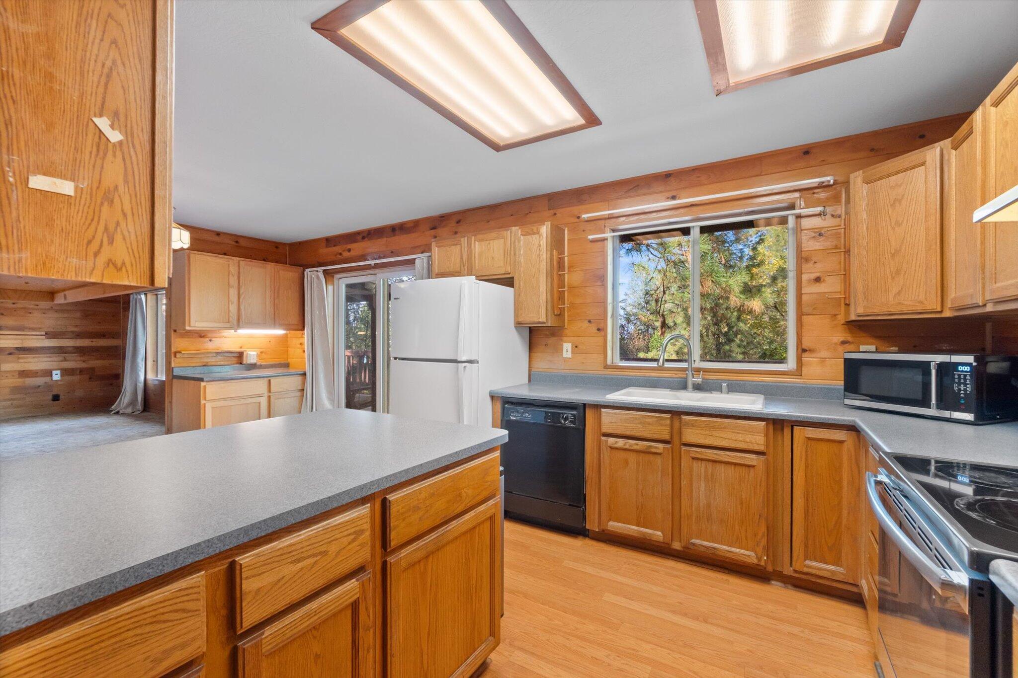 28449 Whippoorwill Circle Shingletown, CA 96088 - Photo 11 of 47 a kitchen with stainless steel appliances granite countertop a refrigerator a sink dishwasher a stove and white countertops with wooden floor