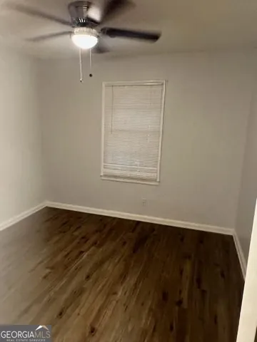an empty room with wooden floor chandelier fan and window