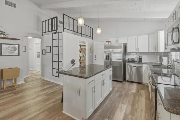 a kitchen with stainless steel appliances granite countertop a sink a stove and refrigerator