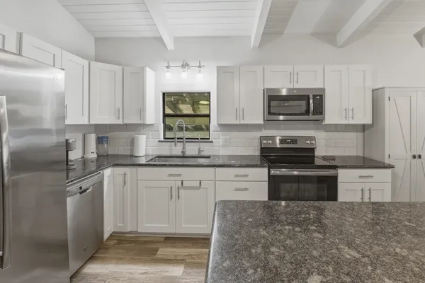 a kitchen with stainless steel appliances granite countertop a stove top oven a sink dishwasher a refrigerator and a microwave