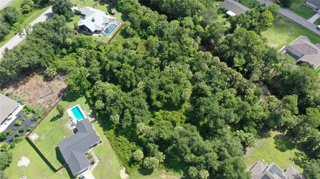 an aerial view of residential house with outdoor space and trees all around