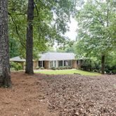 a view of a house with a yard and large trees