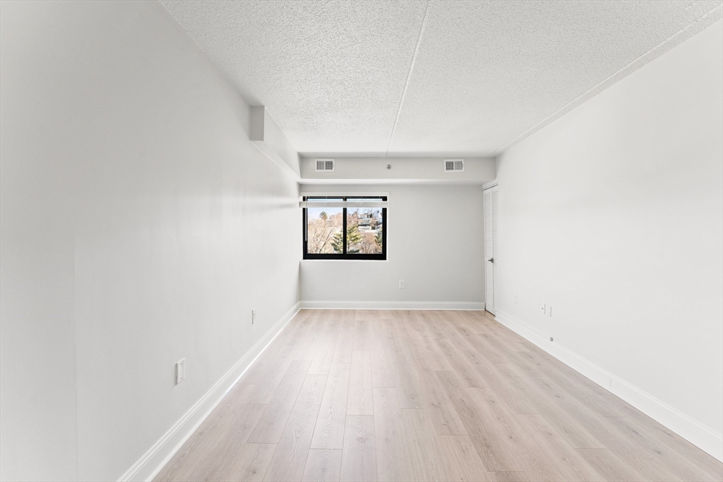 275 Main Street, Unit 205 Watertown, MA 02472 - Photo 33 of 42 an empty room with wooden floor and windows