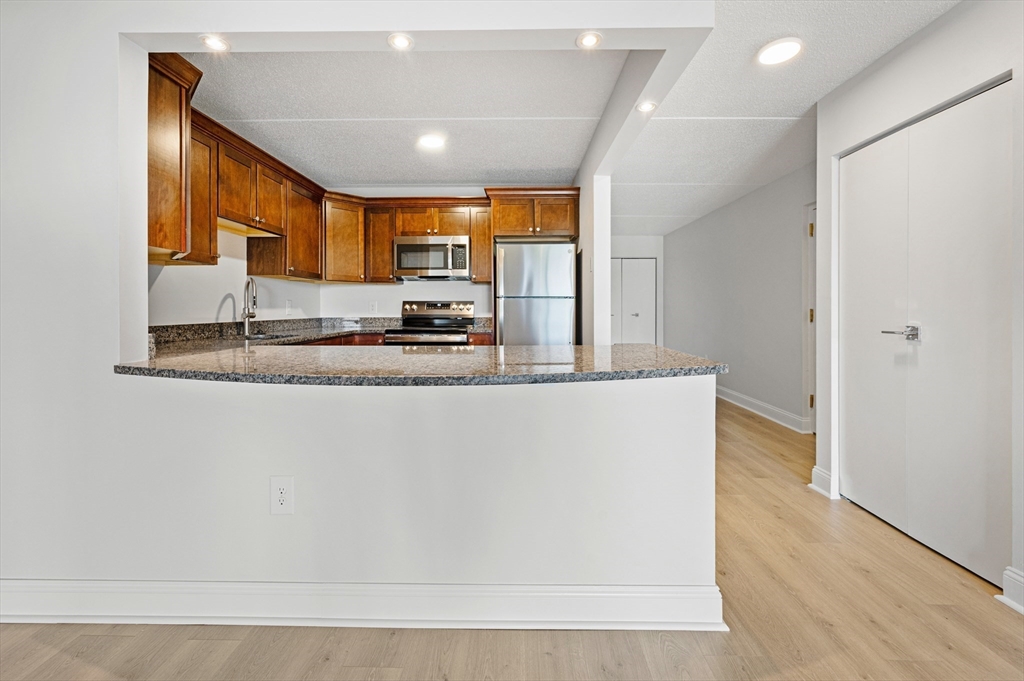 275 Main Street, Unit 205 Watertown, MA 02472 - Photo 7 of 42 a view of a kitchen with kitchen island a sink wooden floor and a counter top space