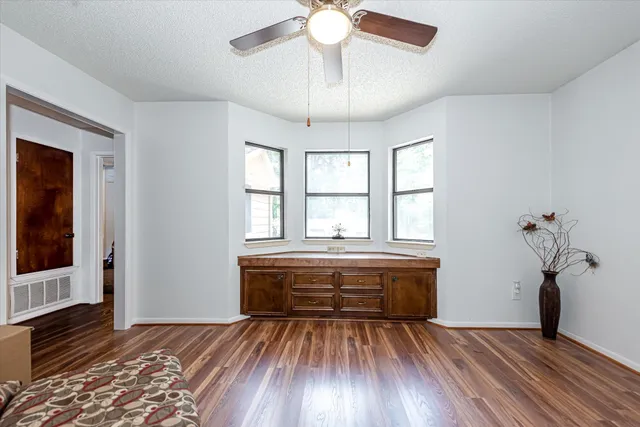 a view of spacious bedroom with wooden floor and fan