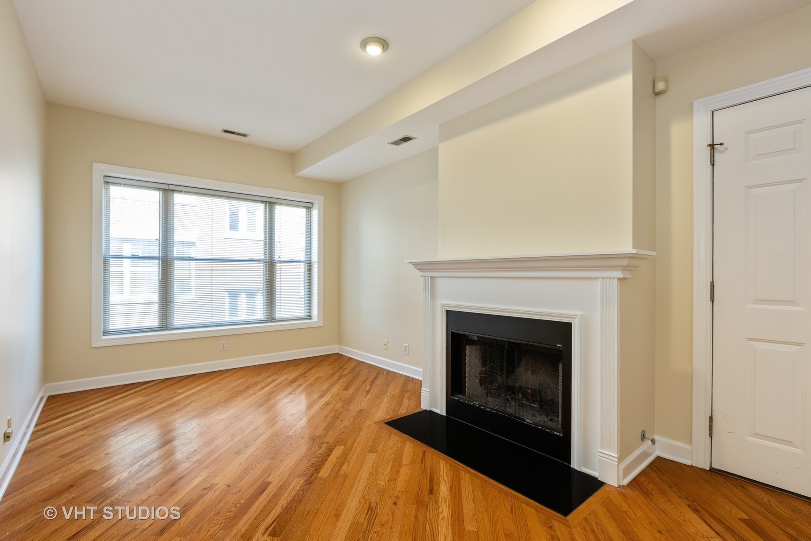 4632 North Racine Avenue, Unit 2 Chicago, IL 60640 - Photo 2 of 12 a view of an empty room with wooden floor fireplace and a window