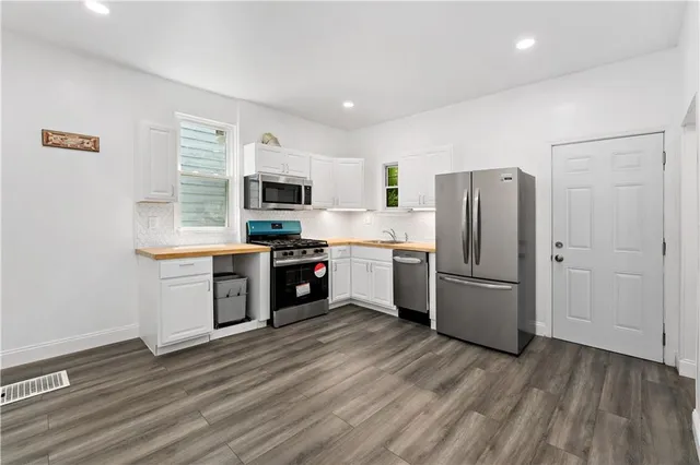 a kitchen with a refrigerator a stove top oven a sink dishwasher and wooden floor