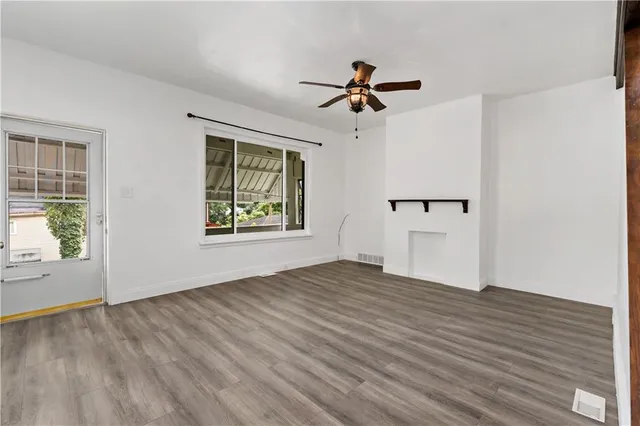a view of an empty room with a window and wooden floor