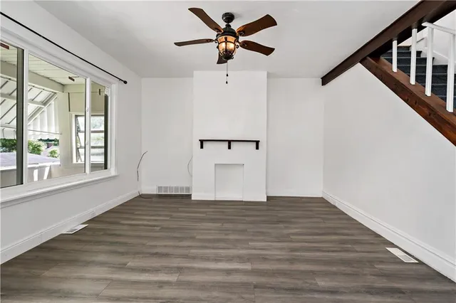 a view of an empty room with window and wooden floor