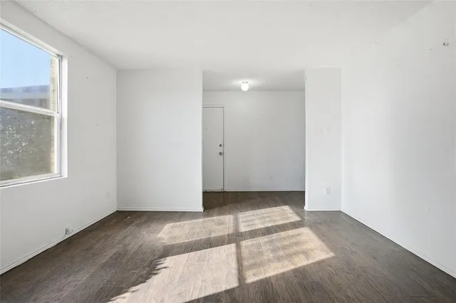 an empty room with wooden floor fan and windows