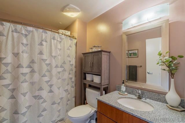 a bathroom with a granite countertop sink toilet a mirror a vanity and shower