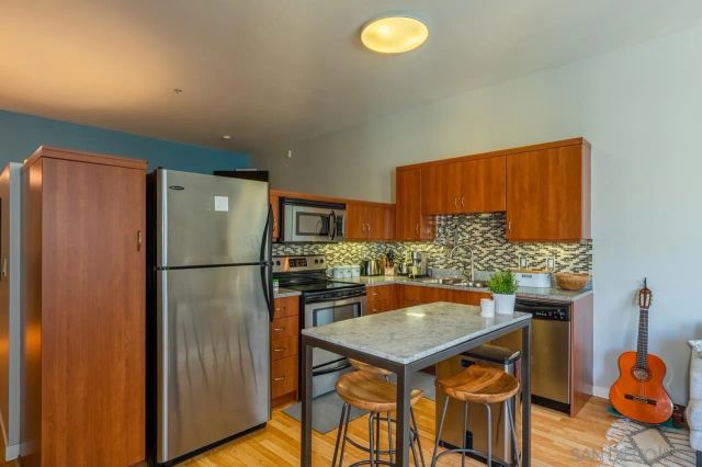 a kitchen with stainless steel appliances granite countertop a refrigerator a stove and a dining table