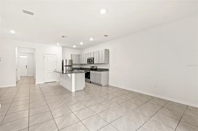 a kitchen with stainless steel appliances kitchen island sink refrigerator and cabinets