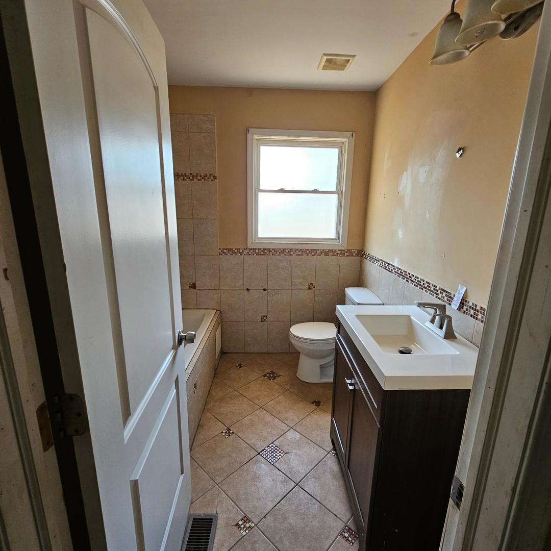 14237 Minerva Avenue Dolton, IL 60419 - Photo 11 of 17 a bathroom with a sink a toilet a mirror and a window