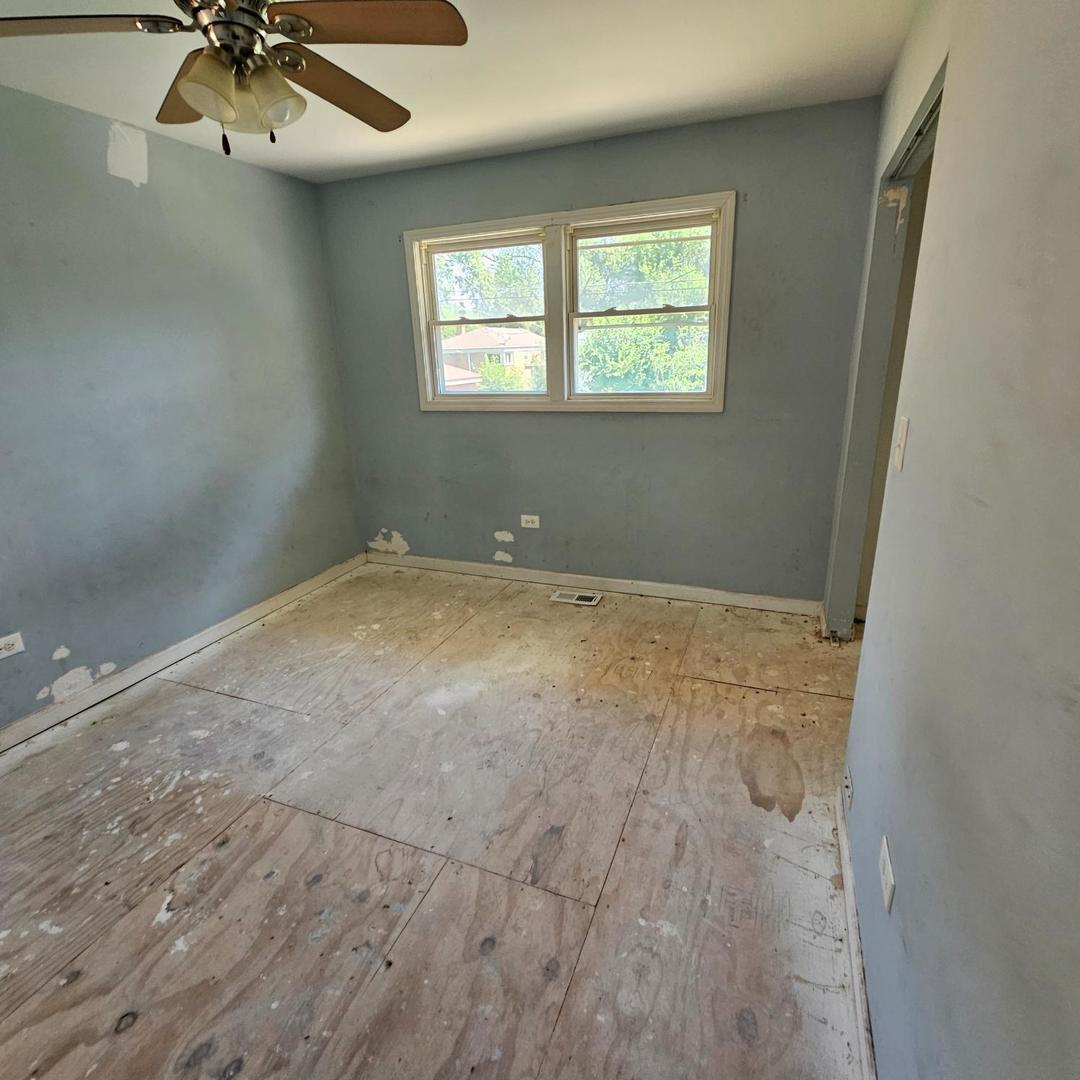 14237 Minerva Avenue Dolton, IL 60419 - Photo 9 of 17 an empty room with a chandelier fan and windows