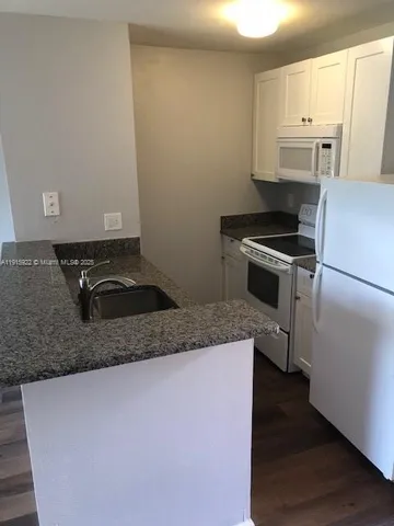 a kitchen with granite countertop a sink stove and refrigerator