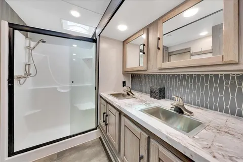 a bathroom with a granite countertop sink a mirror and shower