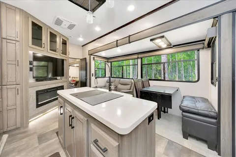 a kitchen with a stove a sink a microwave oven and a dining table with wooden floor