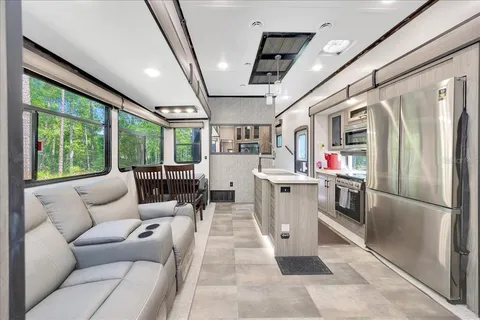 a living room with stainless steel appliances furniture and a large window