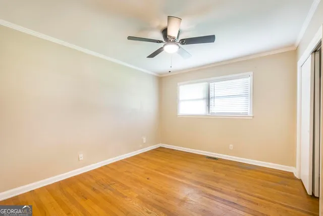 an empty room with wooden floor fan and windows