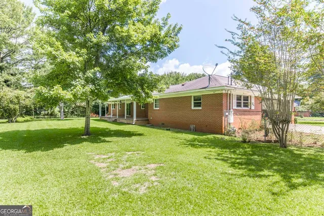 a backyard of a house with plants and large tree