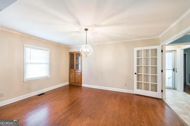 an empty room with wooden floor cabinet and windows