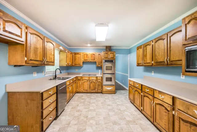 a large kitchen with stainless steel appliances wooden cabinets a stove and a sink