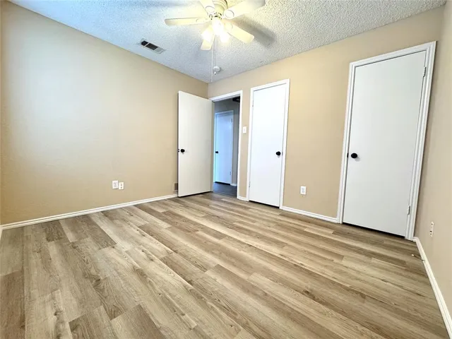 an empty room with wooden floor and fan