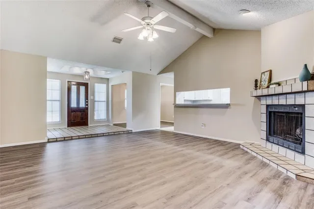 a view of an empty room with wooden floor and a fireplace