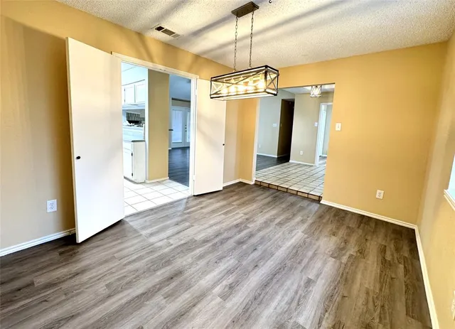 a view of a big room with wooden floor a ceiling fan and kitchen space