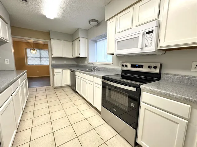 a kitchen with stainless steel appliances granite countertop a stove a sink and a white cabinets