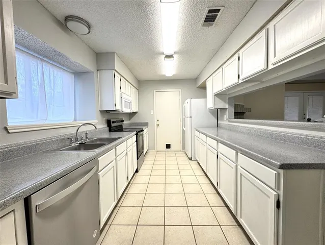 a large white kitchen with a sink and dishwasher a stove top oven with wooden floor