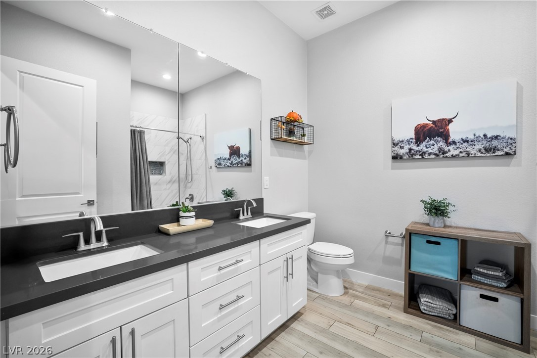 432 North Racetrack Road Henderson, NV 89015 - Photo 21 of 45 Full bathroom with double vanity, a shower with shower curtain, and light wood finished floors