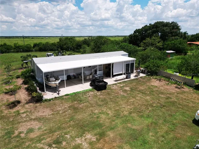 a couple of chairs sitting in big yard with large trees