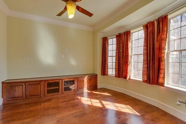 an empty room with wooden floor fan and windows