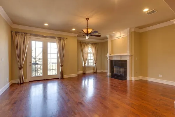 an empty room with wooden floor fireplace and windows