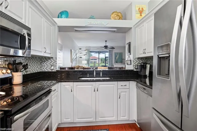 a kitchen with granite countertop a sink stainless steel appliances and white cabinets