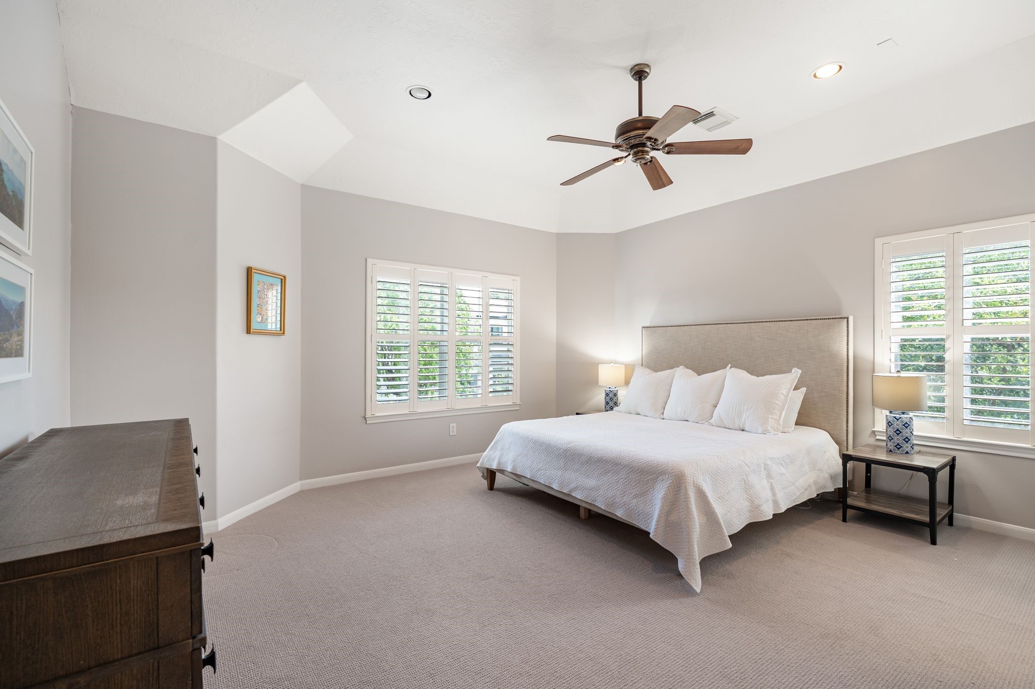 3822 Merrick Street Houston, TX 77025 - Photo 18 of 34 The primary suite is a serene retreat with vaulted ceilings, plush carpet, recessed lighting, a ceiling fan, and plantation shutters on two windows. The elevated ceiling detail adds architectural interest, while the generous room size easily accommodates a full bedroom suite layout.